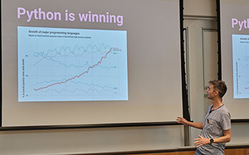 Tom Dyson in front of a screen that reads "Python is winning"